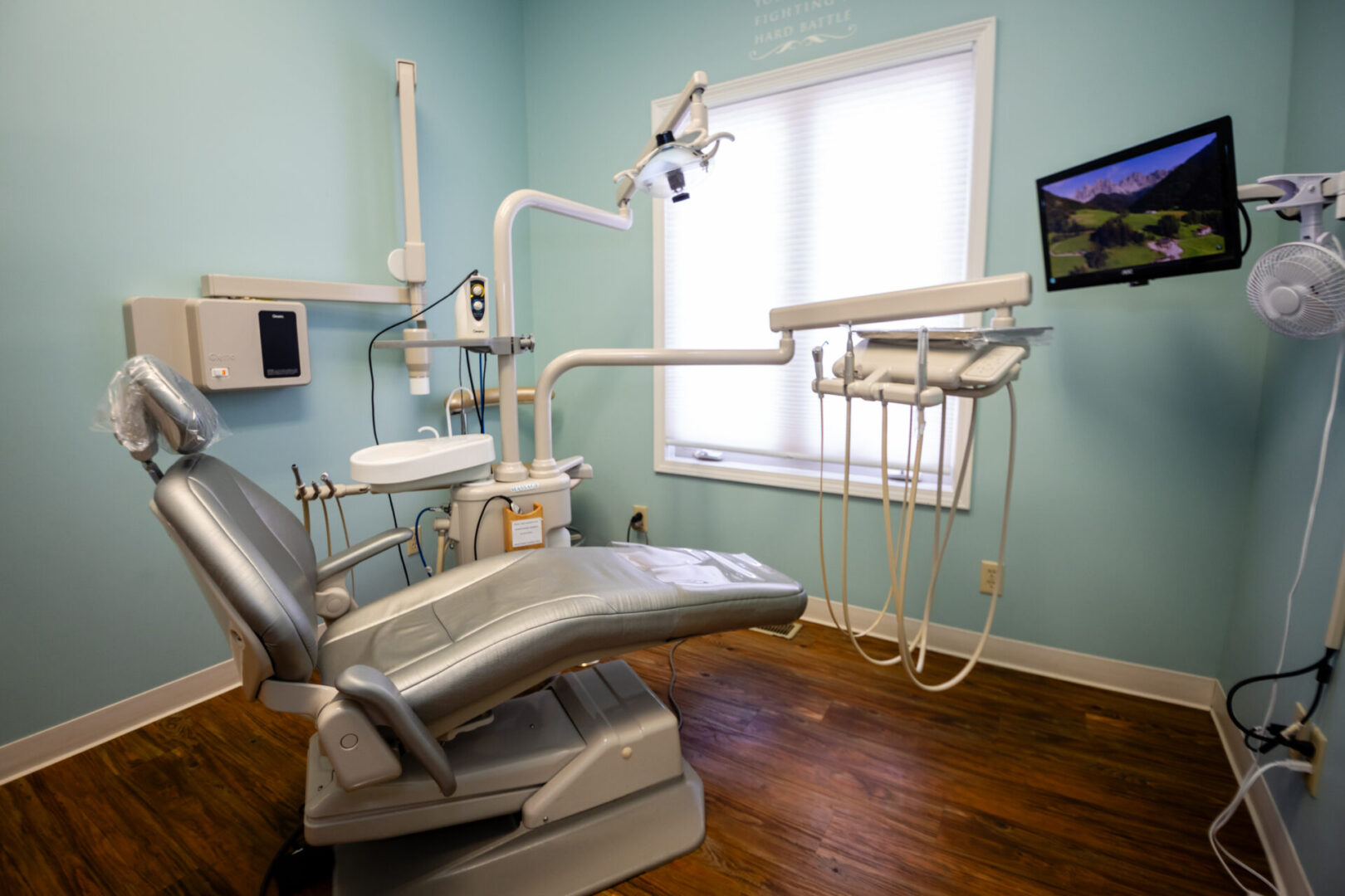 A dentist 's office with a chair and television.