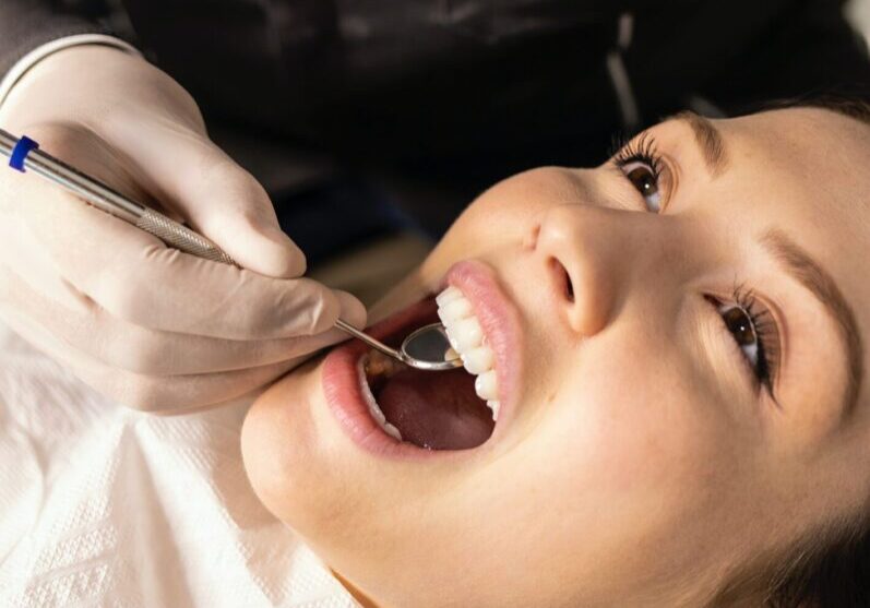 A woman getting her teeth checked by an orthodontist.