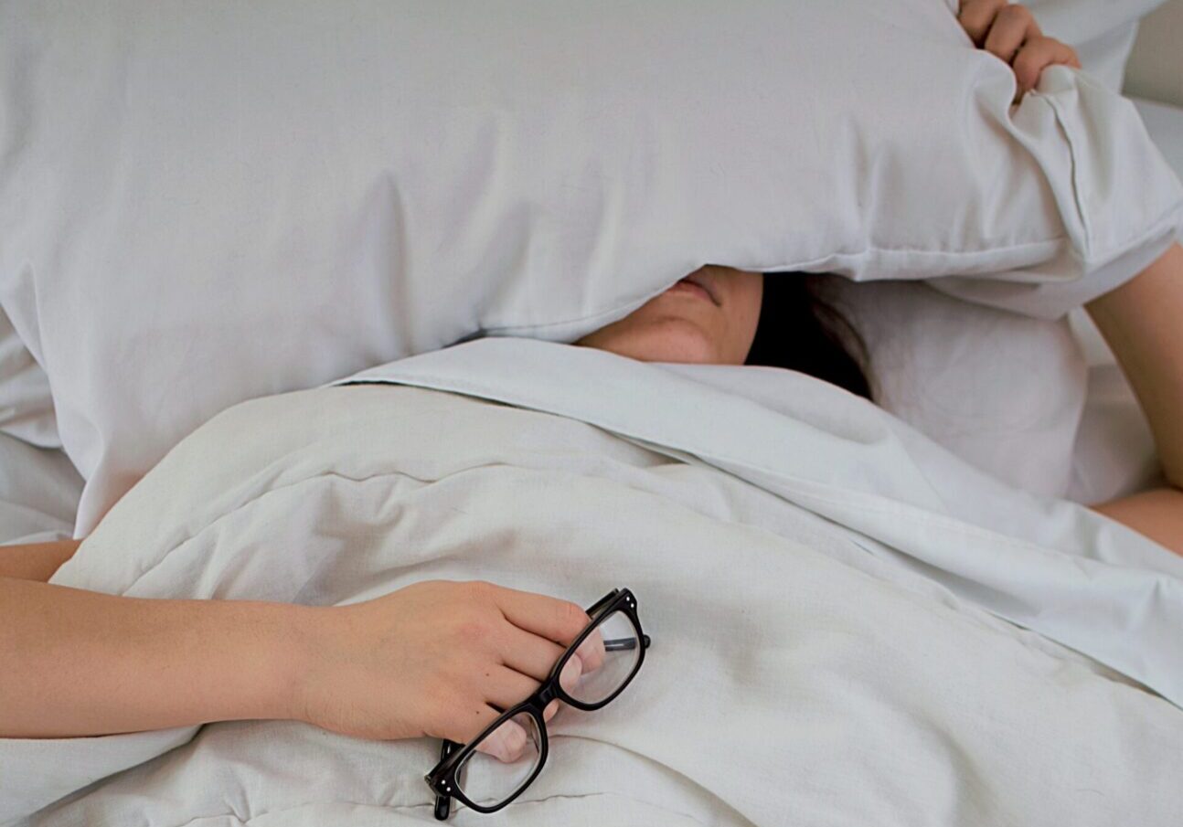 A person laying in bed with pillows and sheets