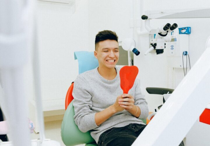 A man sitting in the dentist chair holding an object.